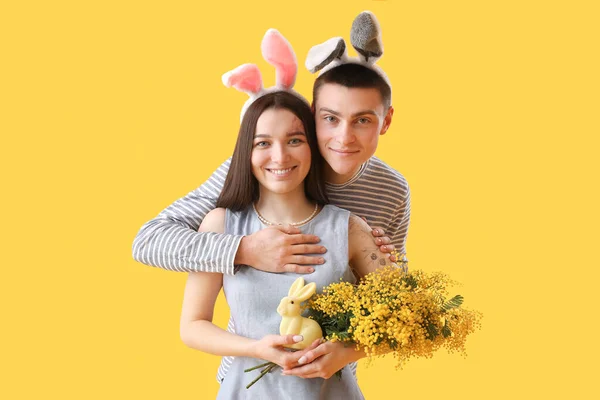 Šťastný Mladý Pár Králičí Uši Mimózou Květiny Žlutém Pozadí Velikonoční — Stock fotografie