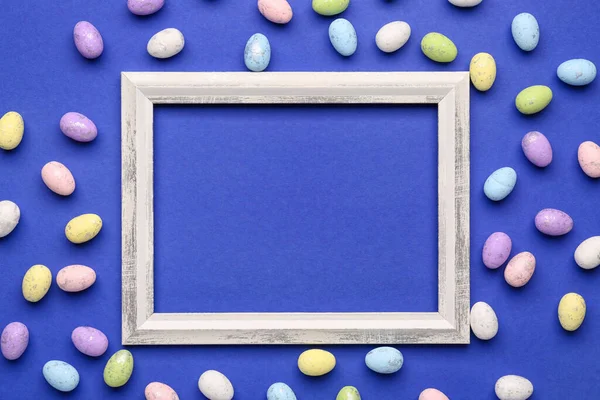 Blank frame and colorful Easter eggs on blue background