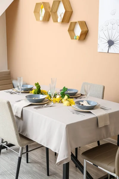Interior of dining room with table served for Easter celebration near beige wall