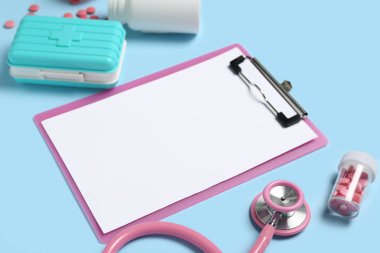 Blank clipboard with medical supplies on blue background. World Health Day