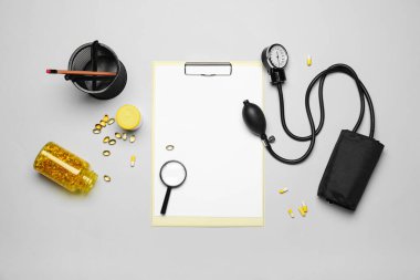 Blank clipboard with magnifier and medical supplies on grey background. World Health Day