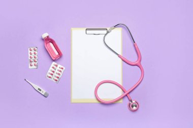 Blank clipboard with medications and thermometer on violet background. World Health Day