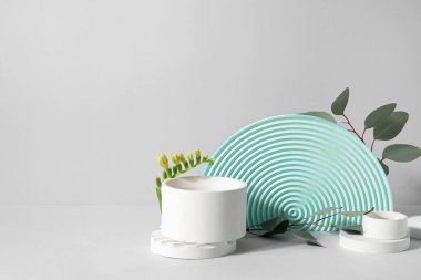 Plaster podiums with freesia flowers and eucalyptus branches on white background