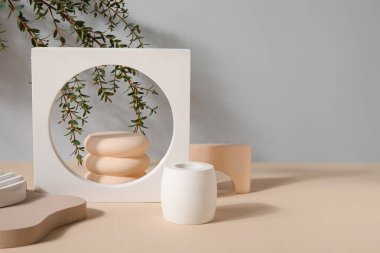 Plaster podiums and eucalyptus branches on beige table against grey background
