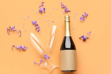Bottle of champagne, glasses, serpentine and sequins on orange background