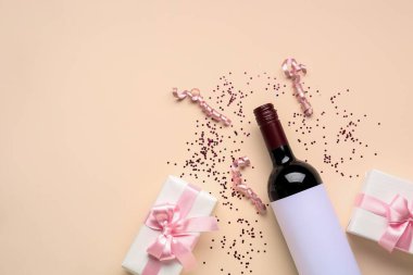 Composition with bottle of wine, gift boxes, serpentine and sequins on beige background