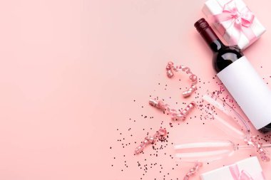 Bottle of wine, gift box, glasses and serpentine on pink background