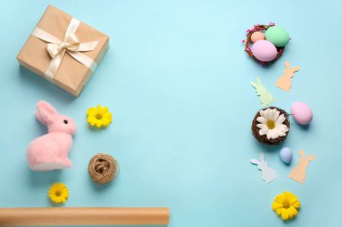 Frame made of gift, Easter eggs, rabbits and flowers on blue background