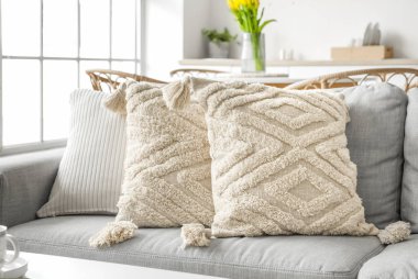 Grey sofa with stylish pillows in kitchen