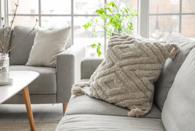 Grey sofa with stylish cushions in light living room