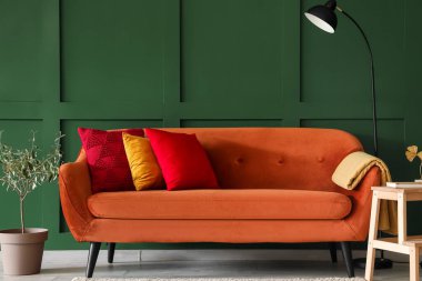 Red sofa with stylish cushions in living room