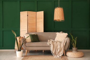 Interior of living room with grey sofa, houseplants and folding screen