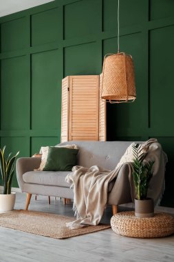 Interior of living room with grey sofa, houseplants and folding screen