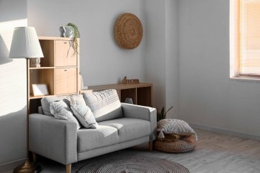 Interior of modern living room with cozy cushions on grey sofa