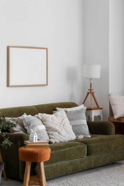 Interior of living room with lamp and cushions on green sofa