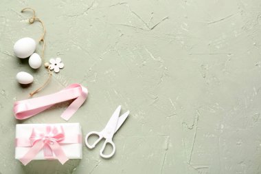 Gift with Easter eggs, scissors and ribbon on grunge background
