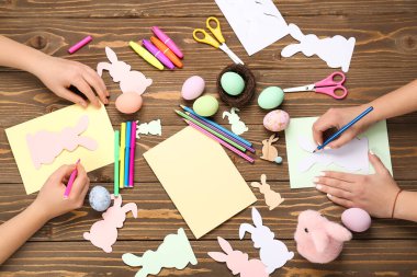 Women making Easter cards on wooden background, top view