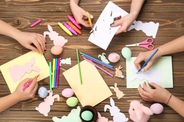 Women making Easter cards on wooden background, top view