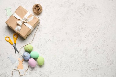 Gift with Easter eggs, scissors and rope on grunge background