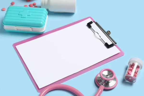 Blank clipboard with medical supplies on blue background. World Health Day