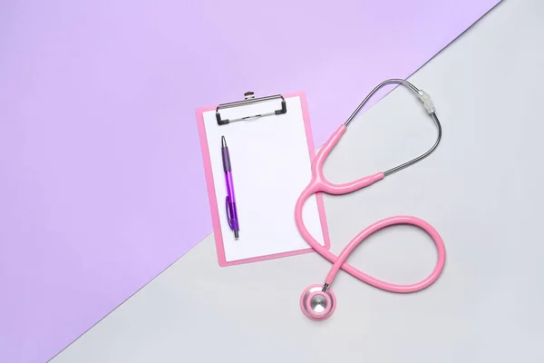 Blank clipboard with pen and stethoscope on color background. World Health Day