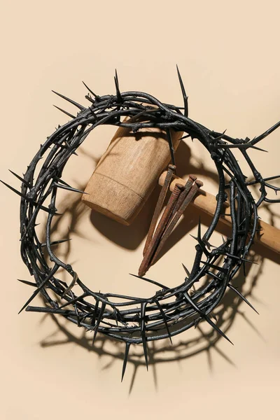 Crown of thorns, mallet and nails on beige background