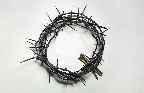 Crown of thorns and nails on light background
