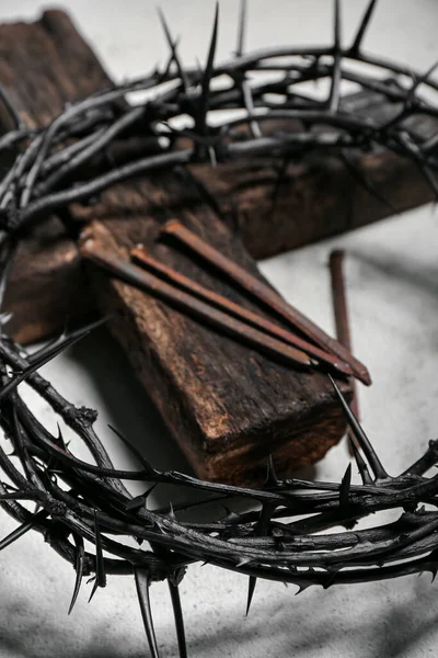 Crown of thorns, wooden cross and nails on grunge background, closeup