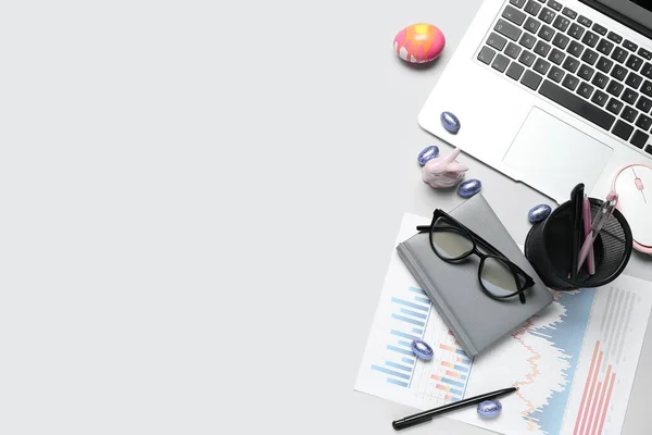 Office stationery with laptop and Easter eggs on grey background