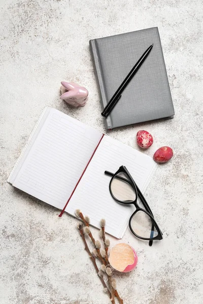 Notebooks with eyeglasses, Easter eggs and willow branches on grunge background