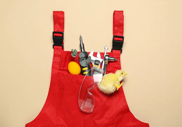 Plumber\'s uniform with tools, Easter egg and chicken on beige background