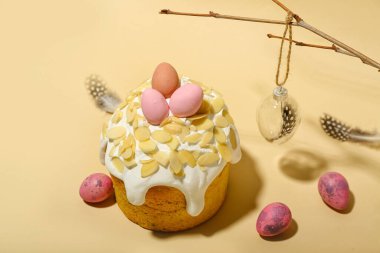 Easter cake, painted eggs and decorations with feathers on beige background