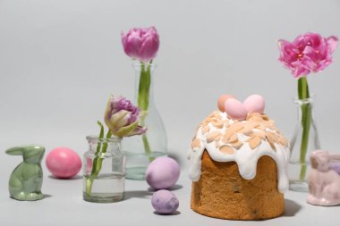 Easter cake, tulip flowers, painted eggs and bunnies on grey background