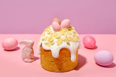 Easter cake, painted eggs and bunny on pink background