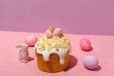 Easter cake, painted eggs and bunny on pink background