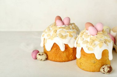 Easter cakes and painted eggs on table near white wall