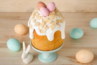 Stand with Easter cake, painted eggs and bunny on wooden background