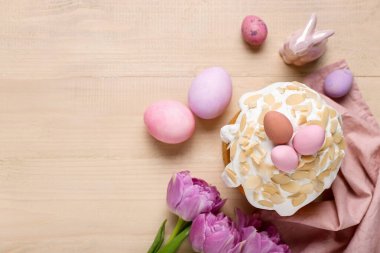 Easter cake, painted eggs, tulip flowers and bunny on wooden background