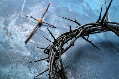 Crown of thorns with wooden cross on blue grunge background. Good Friday concept