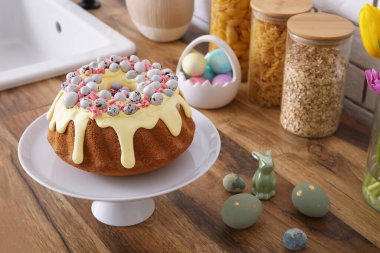 Dessert stand with Easter cake and painted eggs on kitchen counter