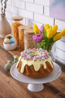 Dessert stand with Easter cake and painted eggs on kitchen counter