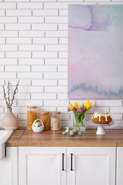 Dessert stand with Easter cake and painted eggs on kitchen counter