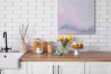 Dessert stand with Easter cake and painted eggs on kitchen counter