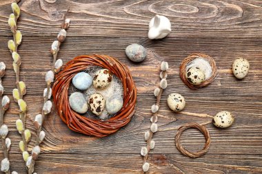 Composition with Easter quail eggs, pussy willow branches and wreaths on wooden background