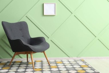Modern grey armchair near green wall