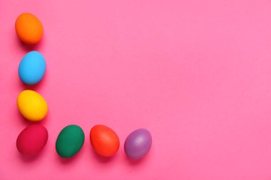 Frame made of colorful Easter eggs on pink background
