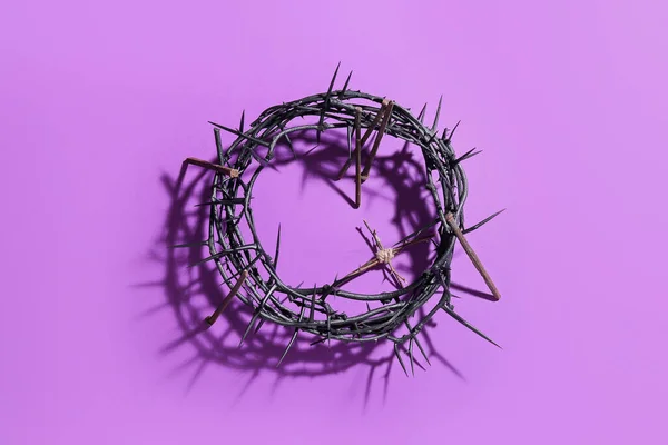 Crown of thorns with wooden cross and nails on violet background. Good Friday concept