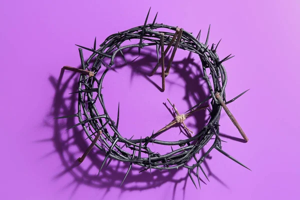 Crown of thorns with wooden cross and nails on violet background. Good Friday concept