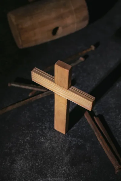 Wooden cross with nails and mallet on dark background, closeup. Good Friday concept