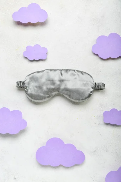 Composition with sleeping mask and paper clouds on light background. World Sleep Day concept